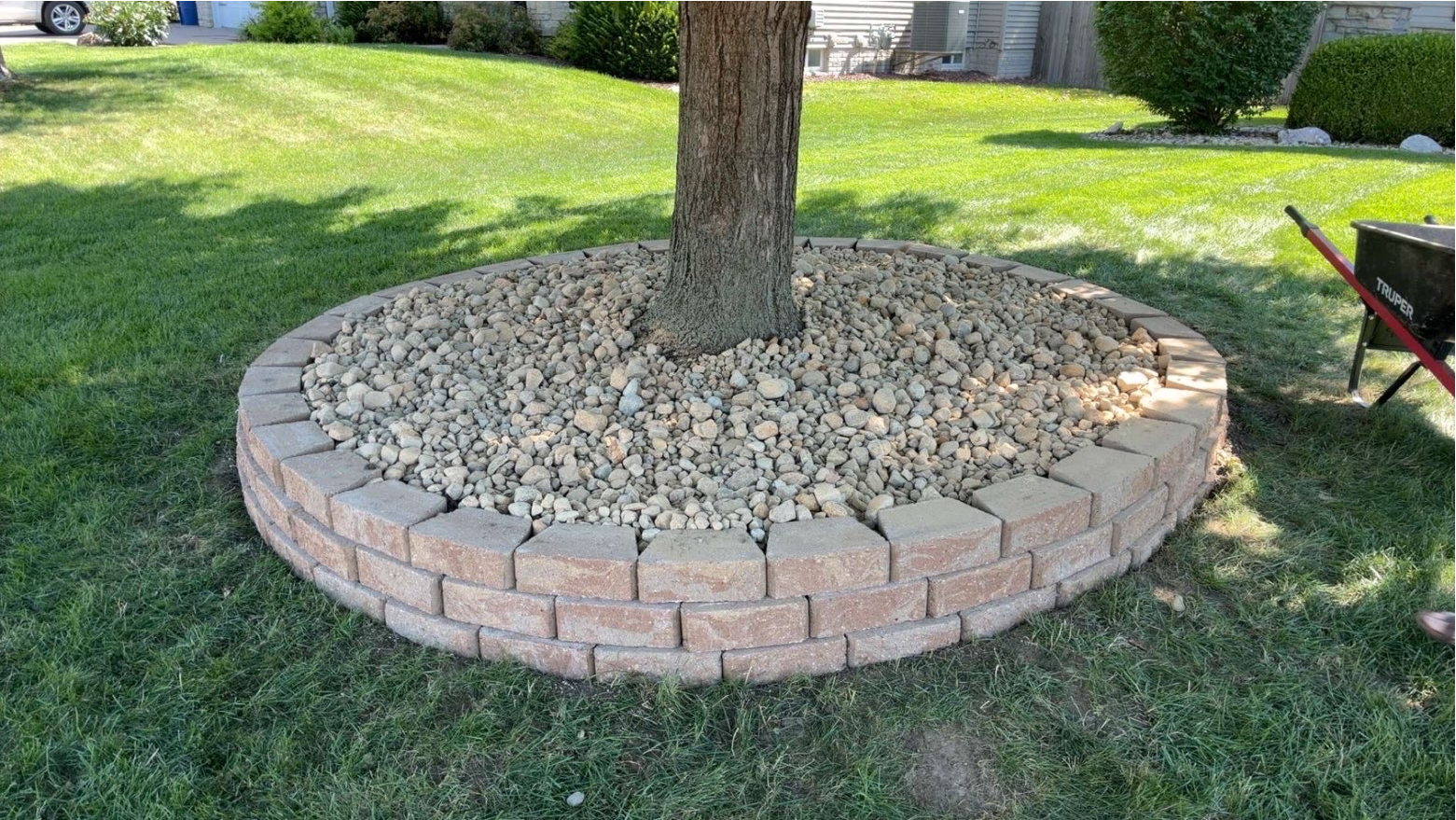 Stone retaining wall ring with river rock around a tree